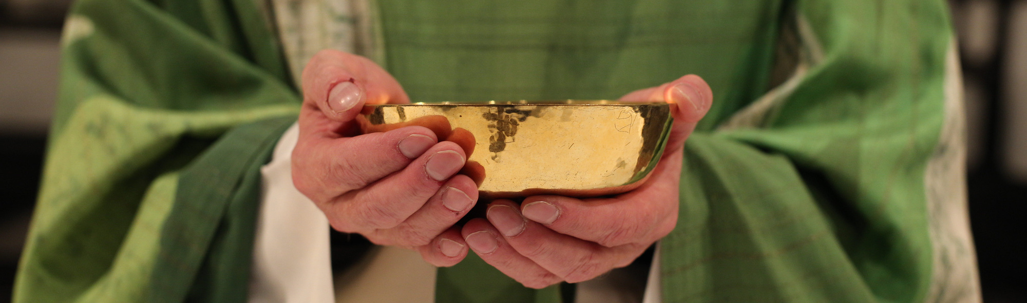 Wandlung Ein Priester hält eine Patene in der Hand.